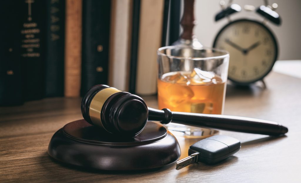 DUI concept. Law gavel, alcohol and car keys on a wooden desk, dark background